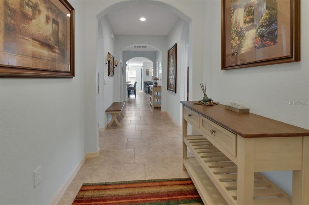 A tiled hallway features arched doorways, framed artwork, and a wooden console table — 217 W CHERRY PLACE, DELAND, FL