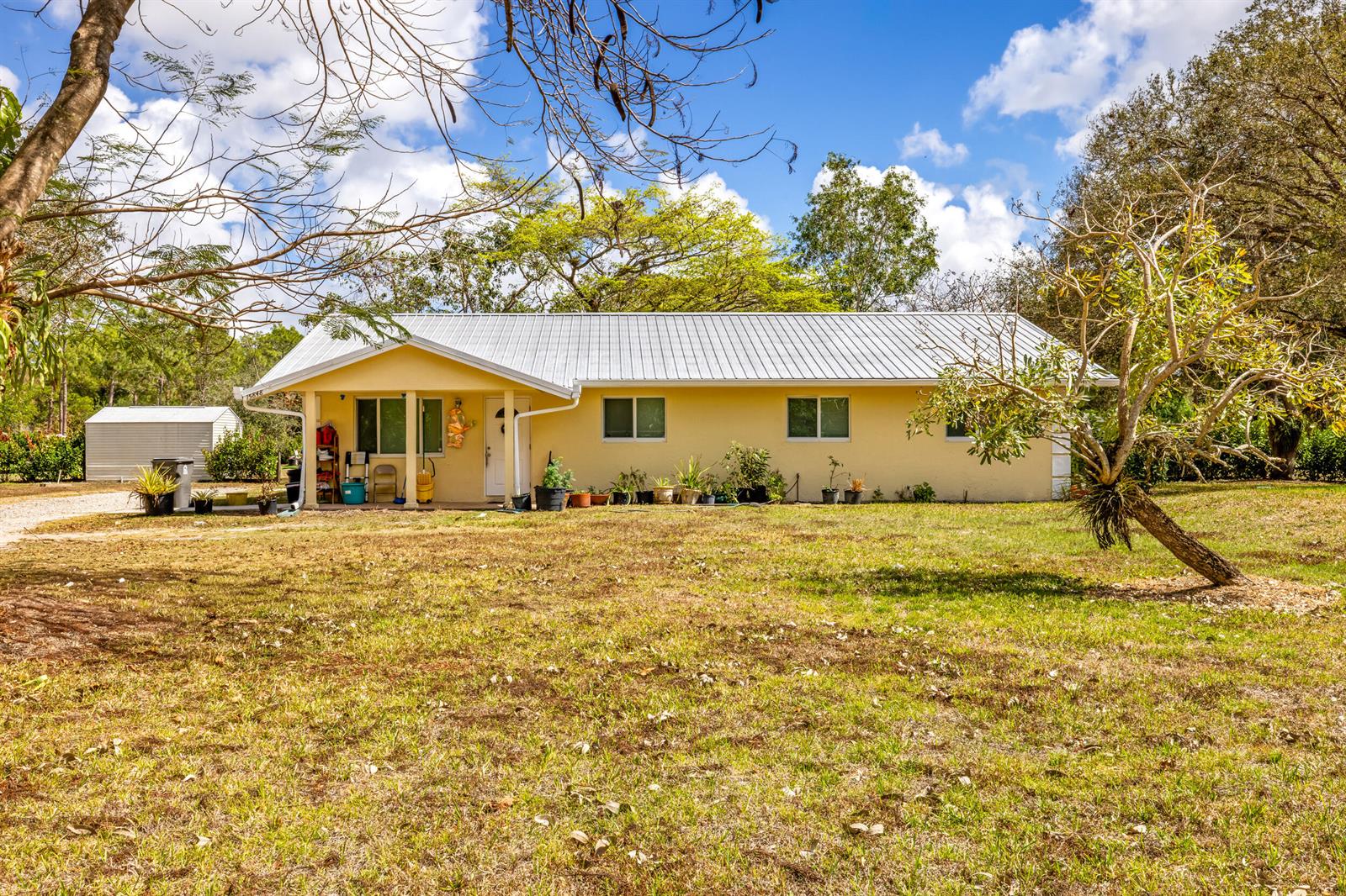 A yellow single-story house with a metal roof sits on a grassy lot — 15848 N 129th Pl N, FL 33478, FL