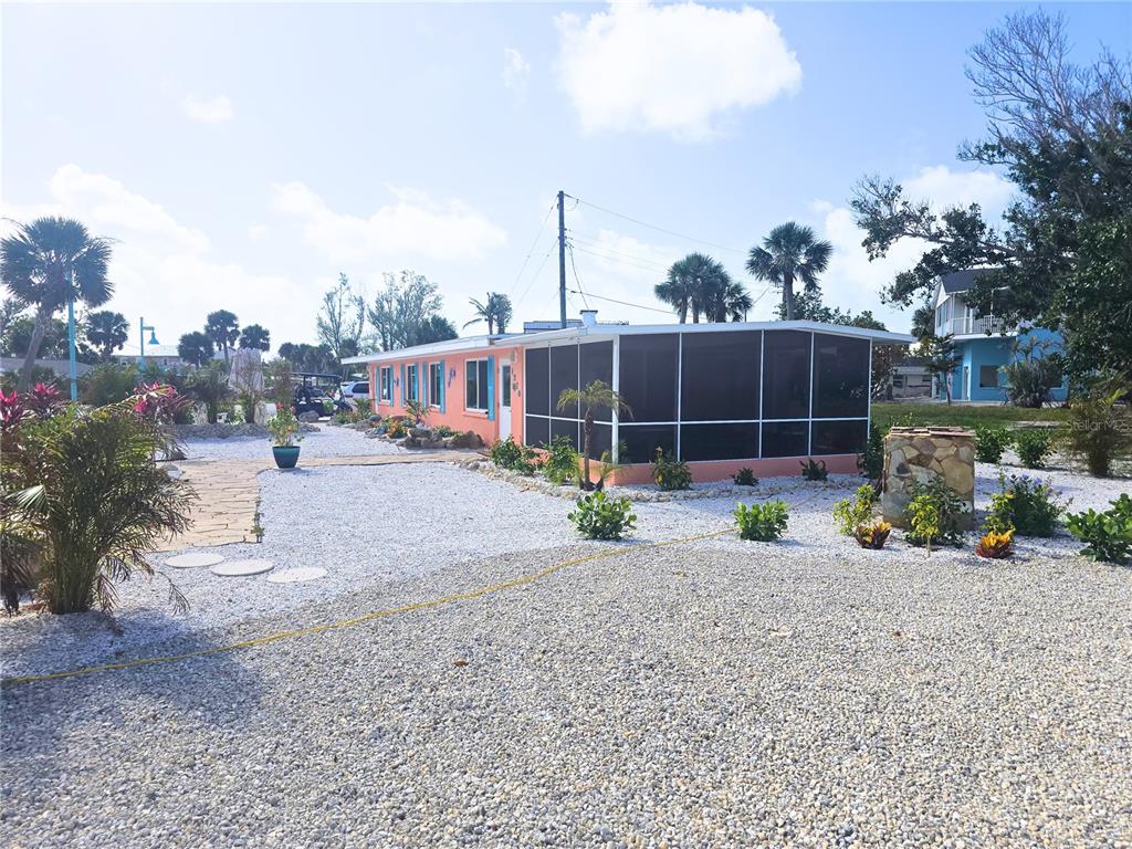 A peach-colored house with a screened-in porch sits on a lot covered in white gravel — 1270 GULF BOULEVARD UNIT A&B, ENGLEWOOD, FL