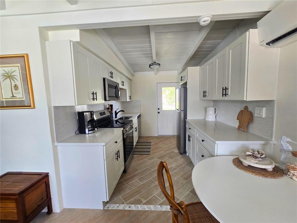 A galley kitchen features white cabinets, stainless steel appliances, and light-colored tile flooring — 1270 GULF BOULEVARD UNIT A&B, ENGLEWOOD, FL