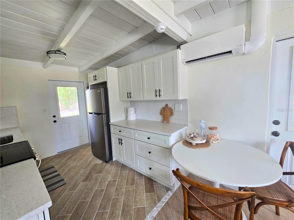 A kitchen features white cabinets, stainless steel appliances, a small dining table, and wood-look flooring — 1270 GULF BOULEVARD UNIT A&B, ENGLEWOOD, FL