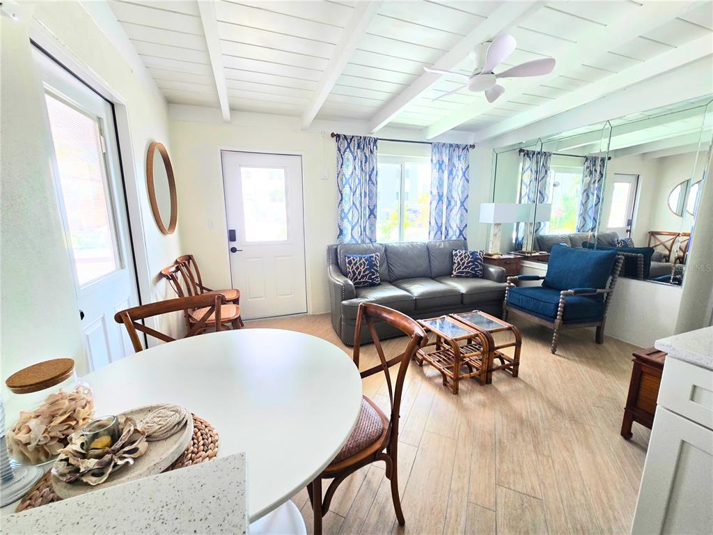 A living room features a gray sofa, blue armchair, white dining table, and mirrored walls — 1270 GULF BOULEVARD UNIT A&B, ENGLEWOOD, FL