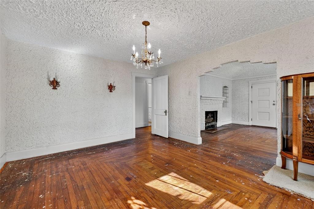 A room with textured walls, a chandelier, and hardwood floors leads to a fireplace area — 5806 N CHEROKEE AVENUE, TAMPA, FL