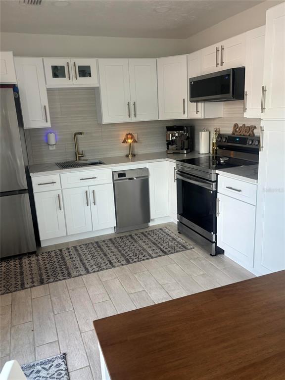 A kitchen features white cabinets, stainless steel appliances, a patterned rug, and light tile flooring — 470 S MCCALL ROAD UNIT 8, ENGLEWOOD, FL