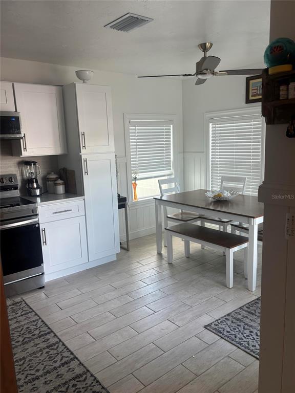 A kitchen with white cabinets, stainless steel appliances, and a dining table with a bench — 470 S MCCALL ROAD UNIT 8, ENGLEWOOD, FL