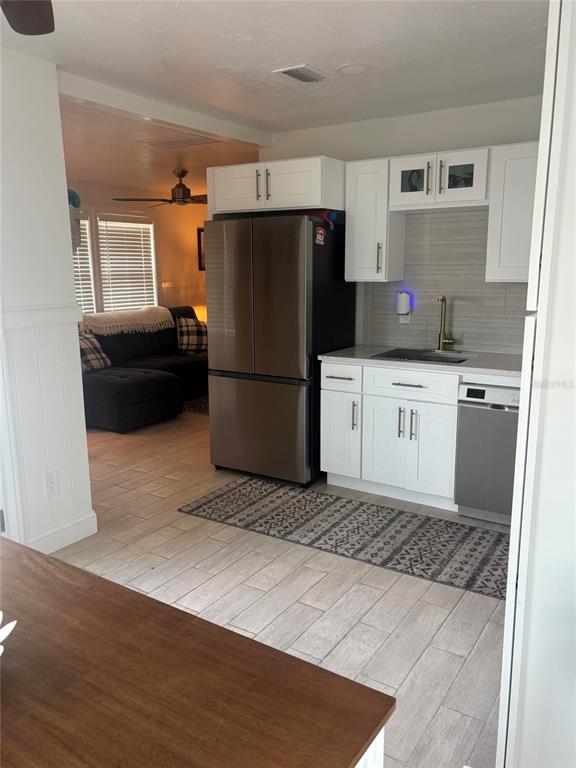 A kitchen with white cabinets, stainless steel appliances, and tile flooring opens to a living area — 470 S MCCALL ROAD UNIT 8, ENGLEWOOD, FL