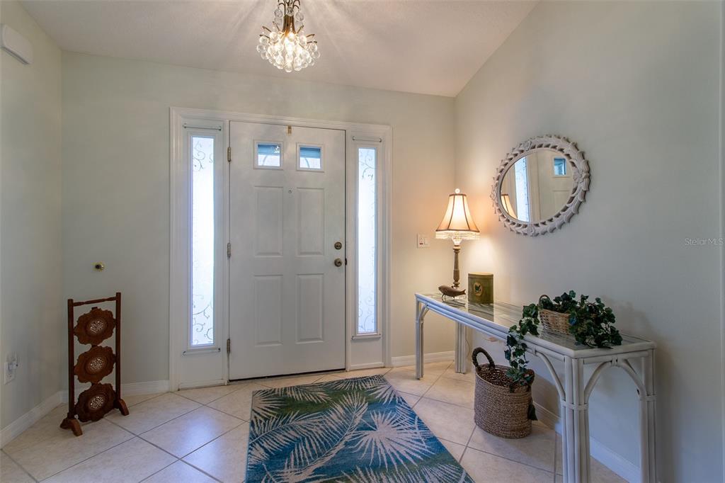 A bright entryway features a white front door with sidelights, tile flooring, and a console table — 15691 SW 11TH COURT ROAD, OCALA, FL