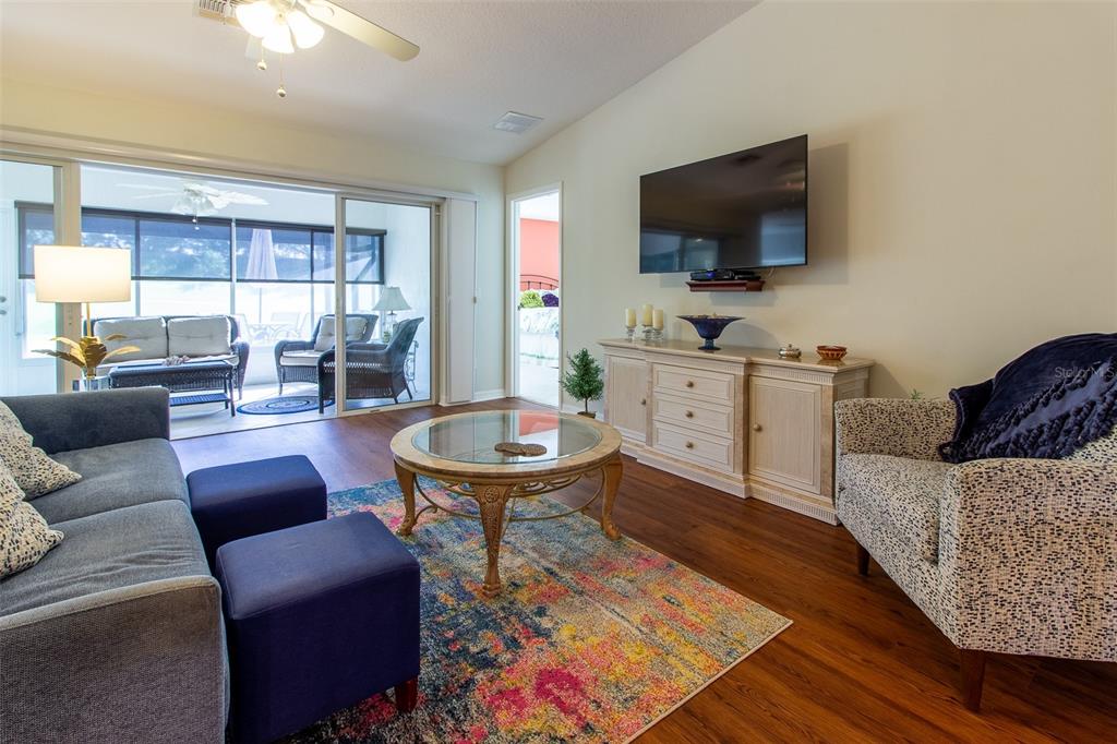A living room features a blue sofa, patterned armchair, coffee table, and a wall-mounted television — 15691 SW 11TH COURT ROAD, OCALA, FL