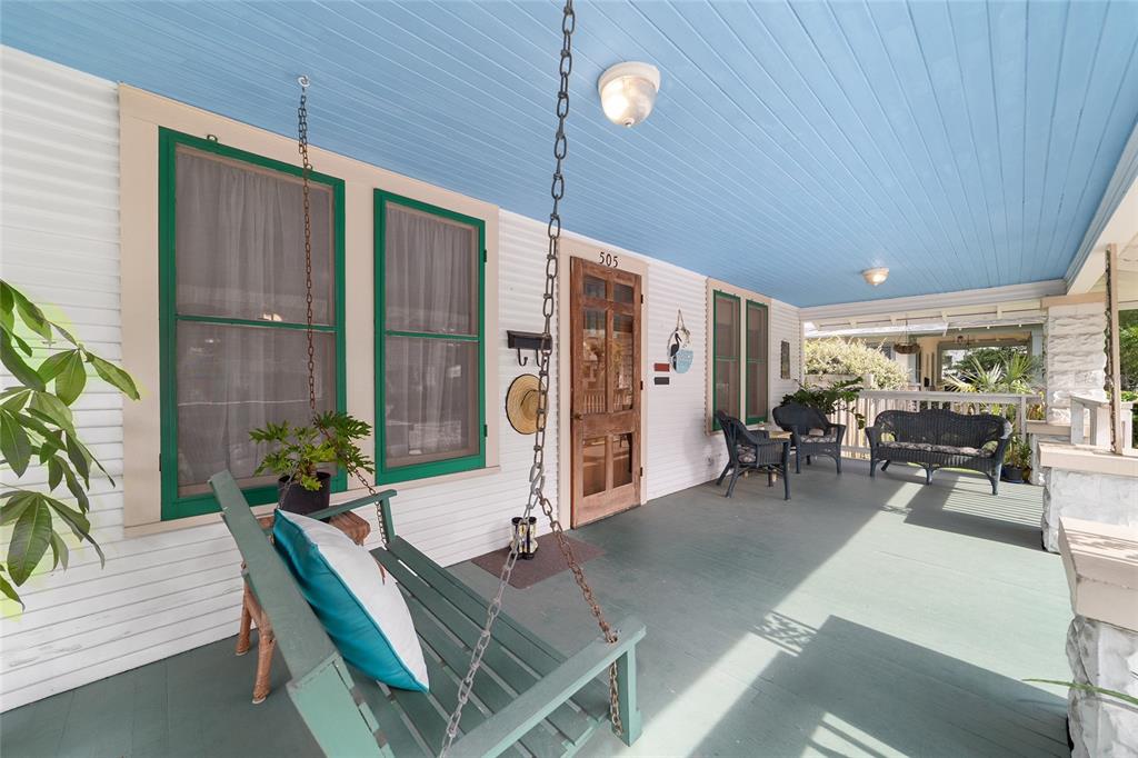 A covered porch features a hanging swing, wicker furniture, and a blue beadboard ceiling — 505 SE SANCHEZ AVENUE, OCALA, FL