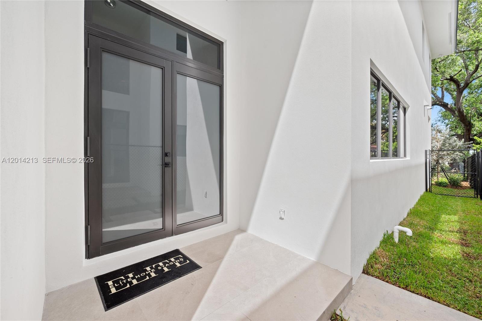 A modern exterior doorway features dark-framed glass doors and a small concrete patio area — 2745 SW 23 Ter, Miami FL 33145, MIAMI, FL