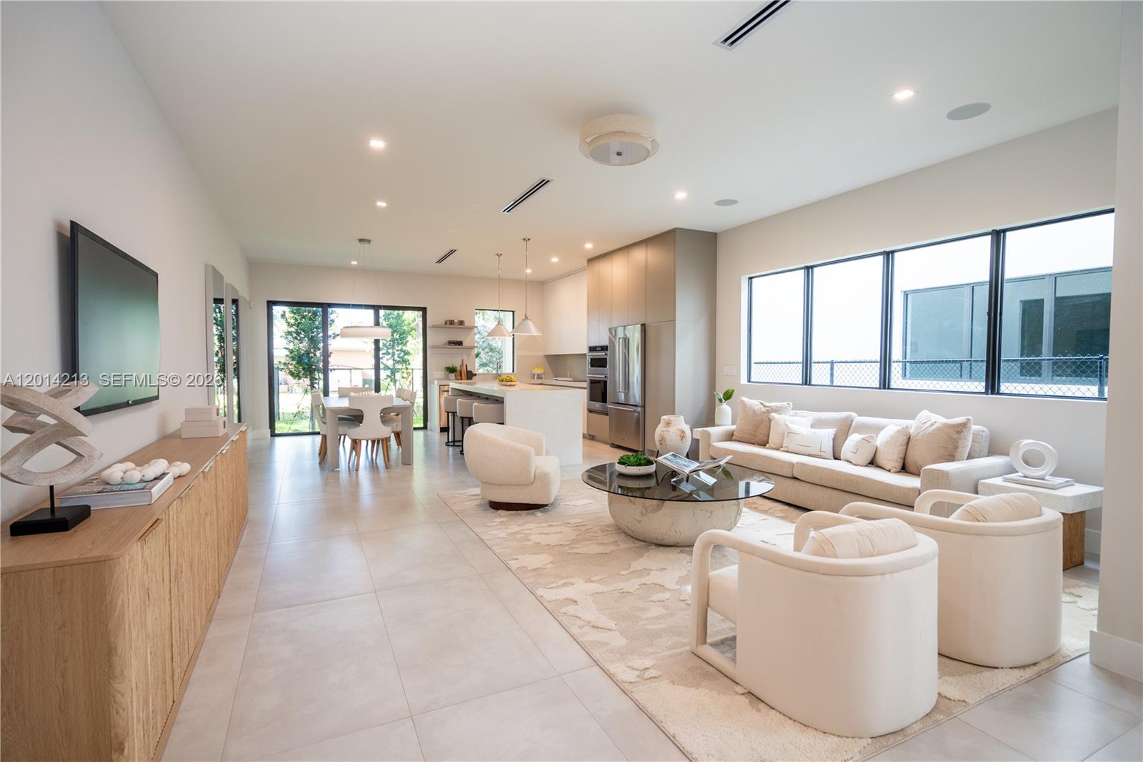 An open-concept living and dining area features a modern kitchen, light flooring, and neutral furniture — 2745 SW 23 Ter, Miami FL 33145, MIAMI, FL