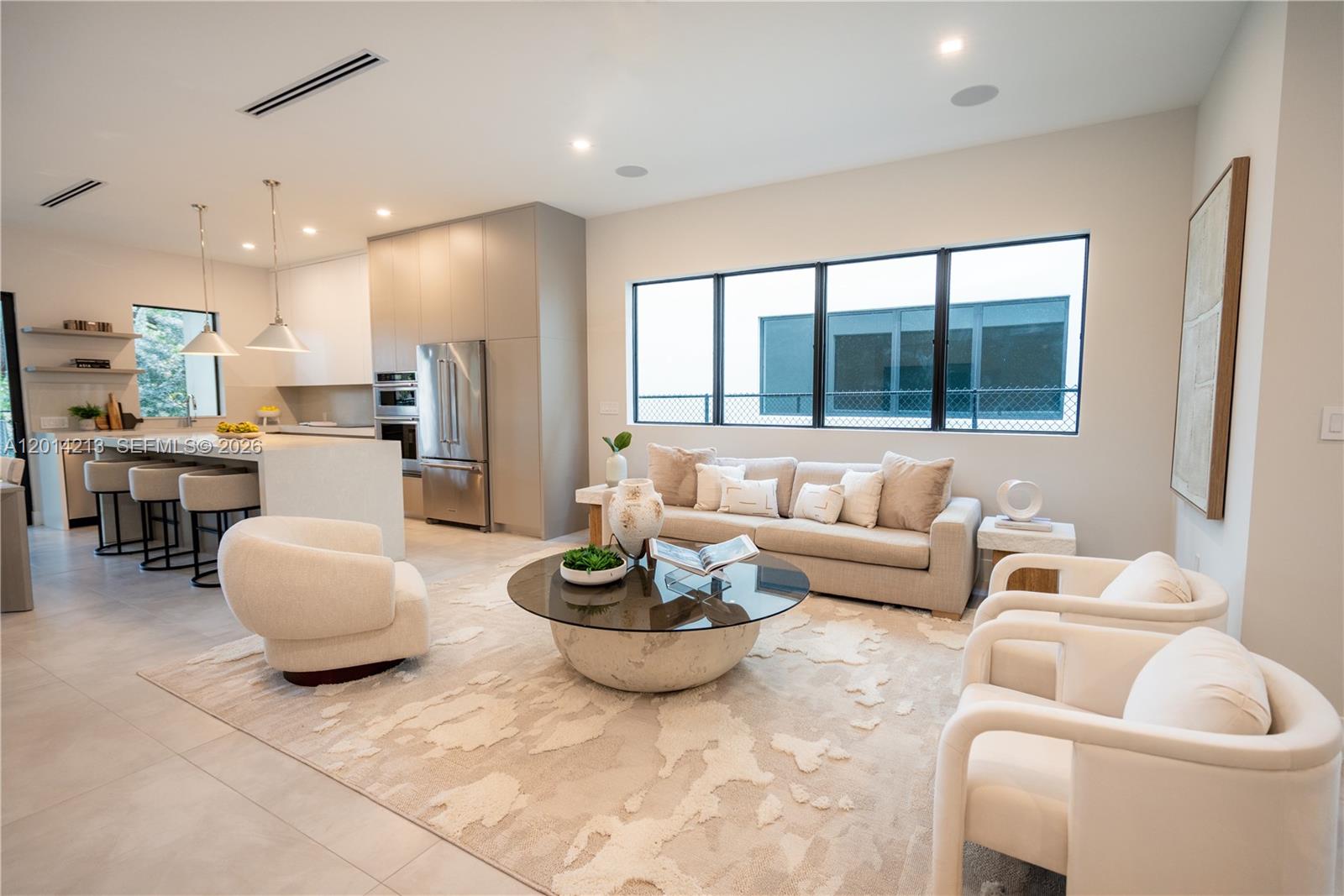 A modern open-concept living room and kitchen feature neutral furniture, a round coffee table, and cabinetry — 2745 SW 23 Ter, Miami FL 33145, MIAMI, FL