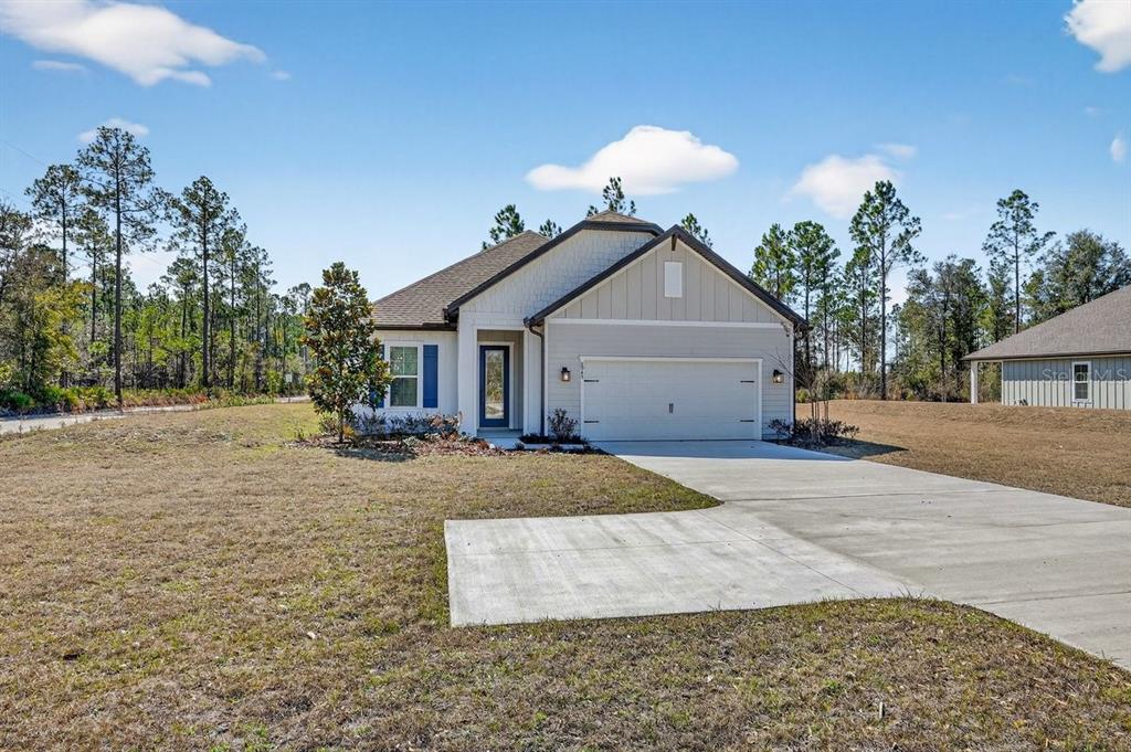 A single-story house with a light-colored exterior, a two-car garage, and a concrete driveway — 8911 FORD ROAD, BRYCEVILLE, FL
