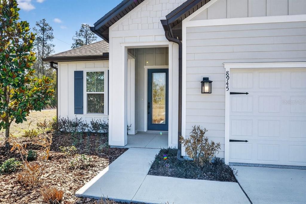 The exterior of a house features a blue front door, white siding, and a garage — 8911 FORD ROAD, BRYCEVILLE, FL