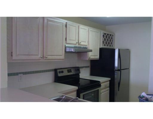 A kitchen features light wood cabinets, stainless steel appliances, and a tiled backsplash — 1845 Palm Cove Boulevard # 301, Delray Beach FL 33445, DELRAY BEACH, FL