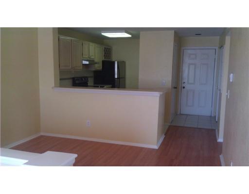 A kitchen with light cabinets and a breakfast bar overlooks a room with wood flooring — 1845 Palm Cove Boulevard # 301, Delray Beach FL 33445, DELRAY BEACH, FL