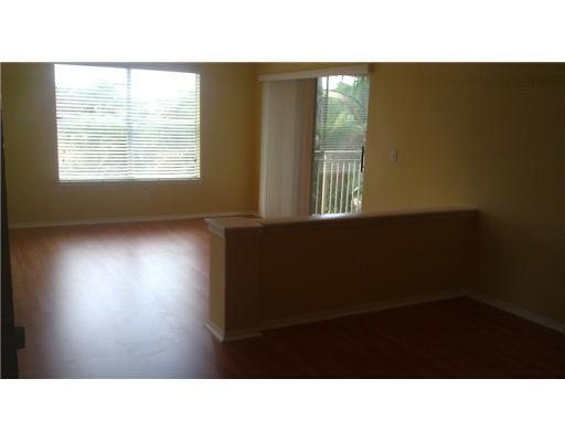 An empty room with wood-look flooring, yellow walls, a large window, and a half wall — 1845 Palm Cove Boulevard # 301, Delray Beach FL 33445, DELRAY BEACH, FL