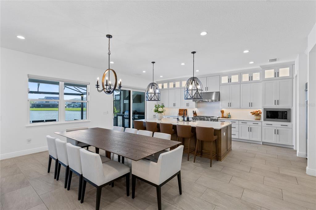A modern open-concept kitchen and dining area with white cabinetry, a large island, and lake views — 9445 SANTORINI DRIVE, ORLANDO, FL