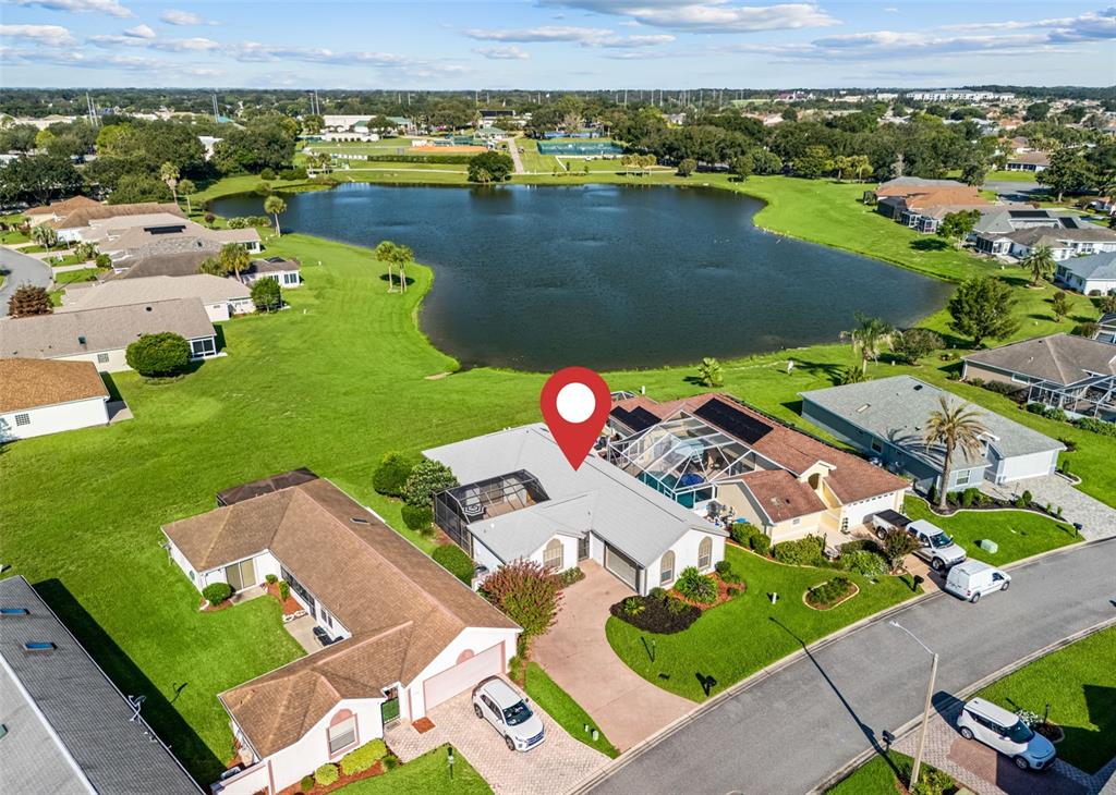 An aerial view shows a suburban house with a pool cage next to a lake — 17742 SE 114TH COURT, SUMMERFIELD, FL