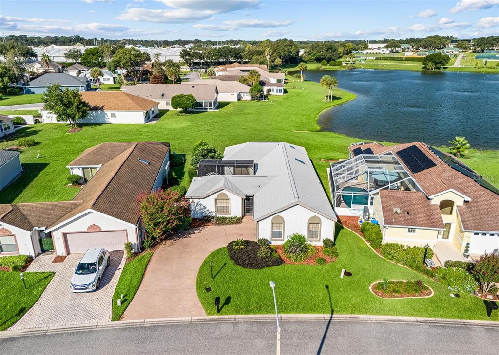 An aerial view shows a suburban house with a metal roof, driveway, and backyard pool — 17742 SE 114TH COURT, SUMMERFIELD, FL
