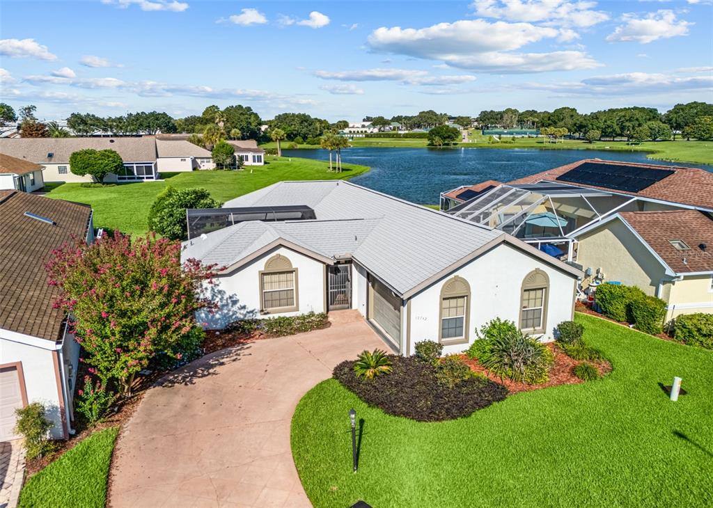 An aerial view of a single-story house with a curved driveway and a backyard lake — 17742 SE 114TH COURT, SUMMERFIELD, FL