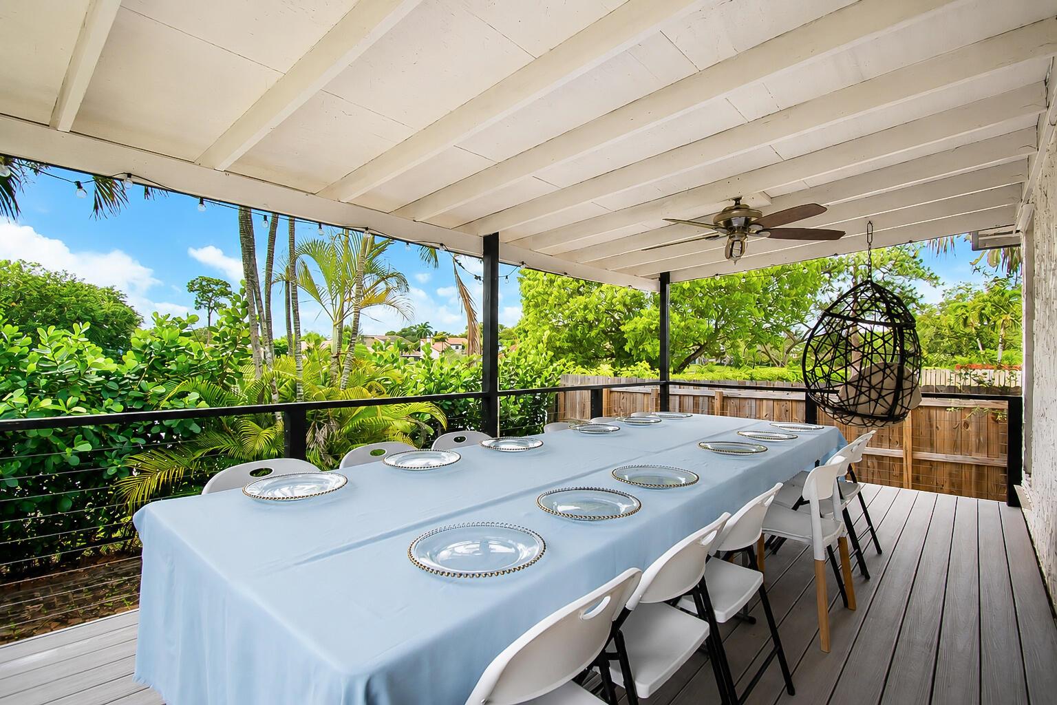 A covered outdoor deck features a long dining table with white chairs and a hanging chair — 6458 Pond Apple Road, Boca Raton FL 33433, BOCA RATON, FL