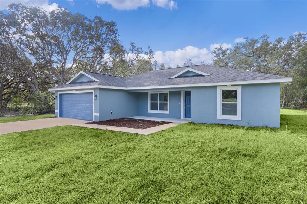 A blue single-story house with a two-car garage and a front lawn — 18 FISHER TERRACE WAY, OCKLAWAHA, FL