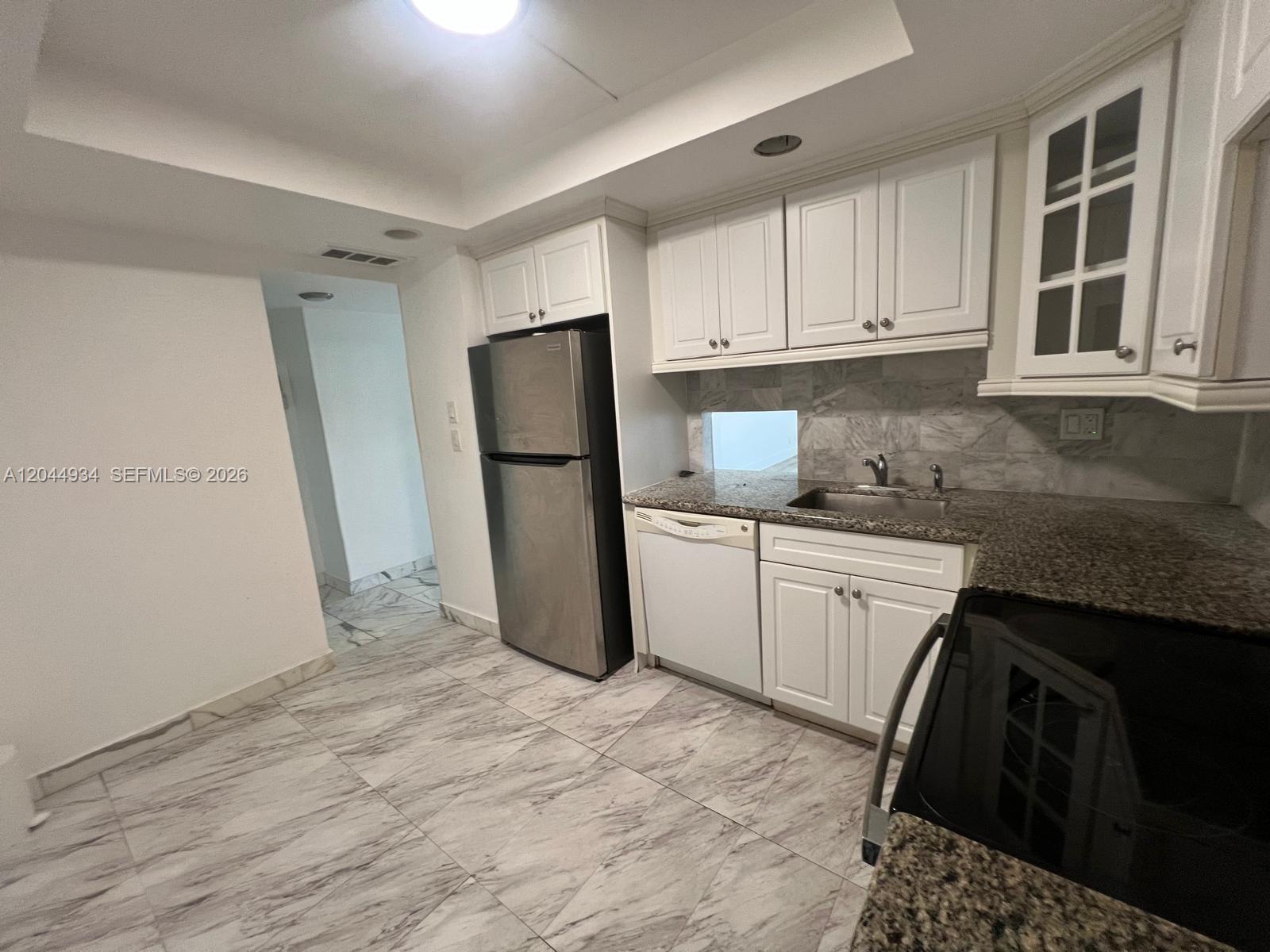 A kitchen features white cabinets, granite countertops, stainless steel appliances, and marble-patterned tile flooring — 1600 S Ocean Dr # 18C, Hollywood FL 33019, HOLLYWOOD, FL