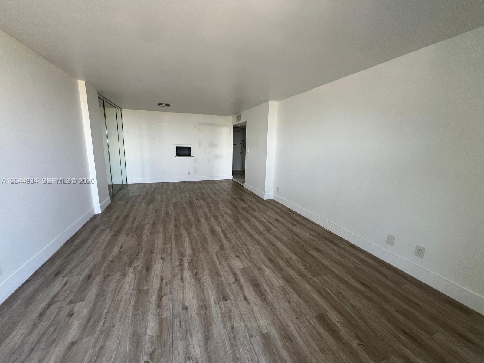 An empty room features white walls, wood-look flooring, and a recessed wall niche — 1600 S Ocean Dr # 18C, Hollywood FL 33019, HOLLYWOOD, FL