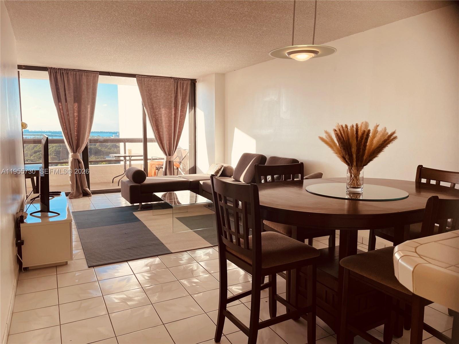 A living and dining area with tile floors, a sectional sofa, and a balcony view — 2555 Collins Ave # 1804, Miami Beach FL 33140, MIAMI BEACH, FL
