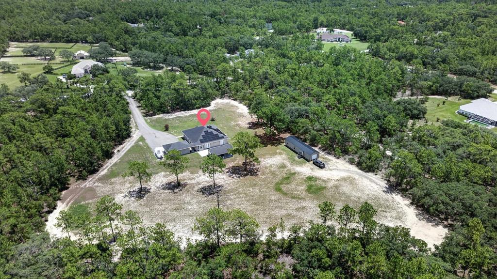 An aerial view shows a house with solar panels on a large, wooded lot — 3274 N BRAVO DRIVE, BEVERLY HILLS, FL