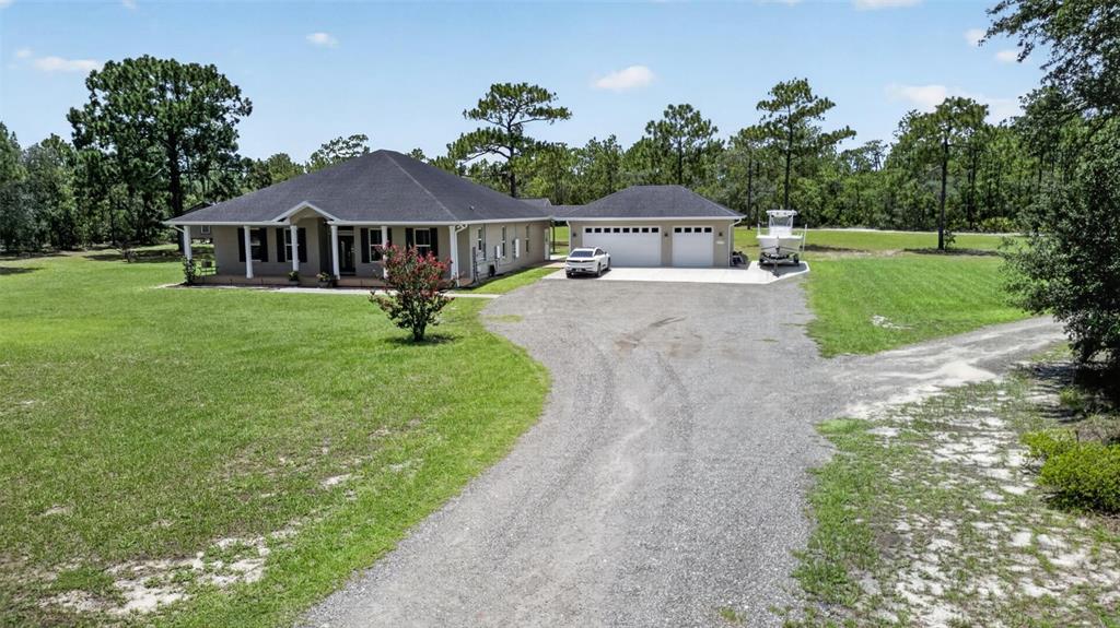 A single-story house with a dark roof, attached garage, and a gravel driveway — 3274 N BRAVO DRIVE, BEVERLY HILLS, FL