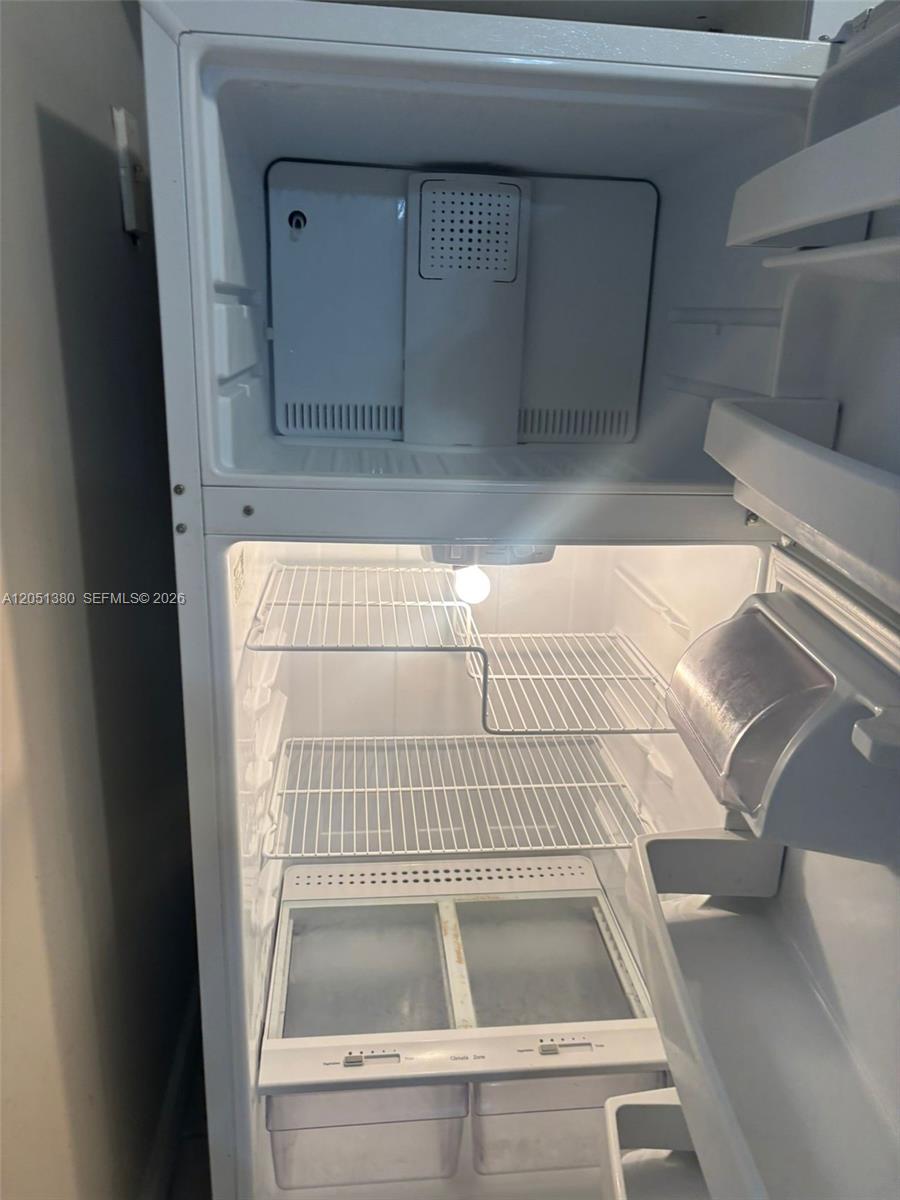 An open white top-freezer refrigerator with wire shelves and two crisper drawers — DEERFIELD BEACH, FL