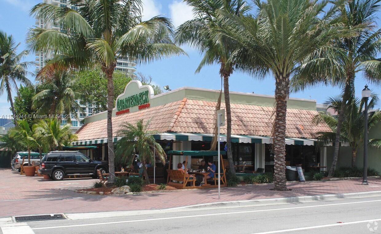 An exterior view of a restaurant with a tiled roof, palm trees, and outdoor seating — FORT LAUDERDALE, FL