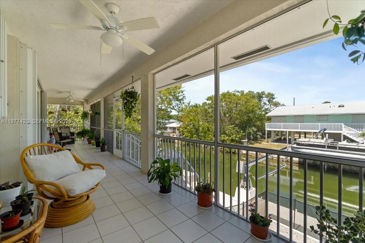 A screened-in porch features tile flooring, a ceiling fan, and a view of a canal — 29051 Magnolia Ln, Big Pine FL 33043, BIG PINE, FL