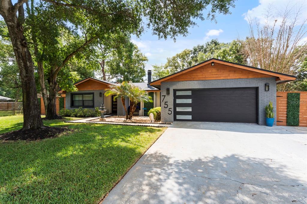 A single-story house with a gray brick exterior, wood accents, and a modern garage door — 755 WOODSIDE ROAD, MAITLAND, FL