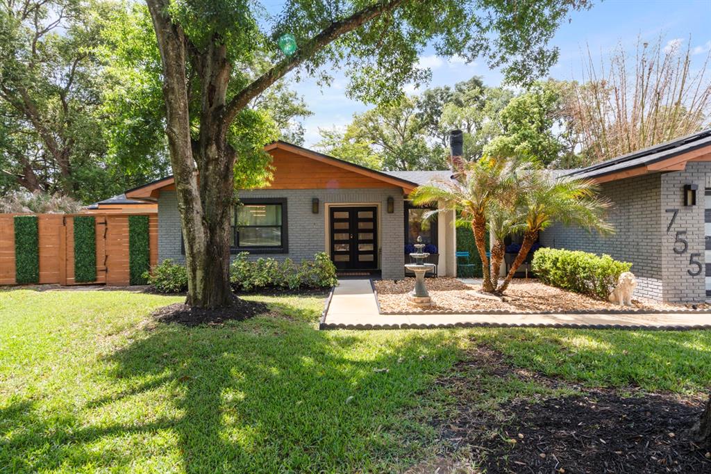 A single-story house with gray brick, wood accents, a palm tree, and a front walkway — 755 WOODSIDE ROAD, MAITLAND, FL