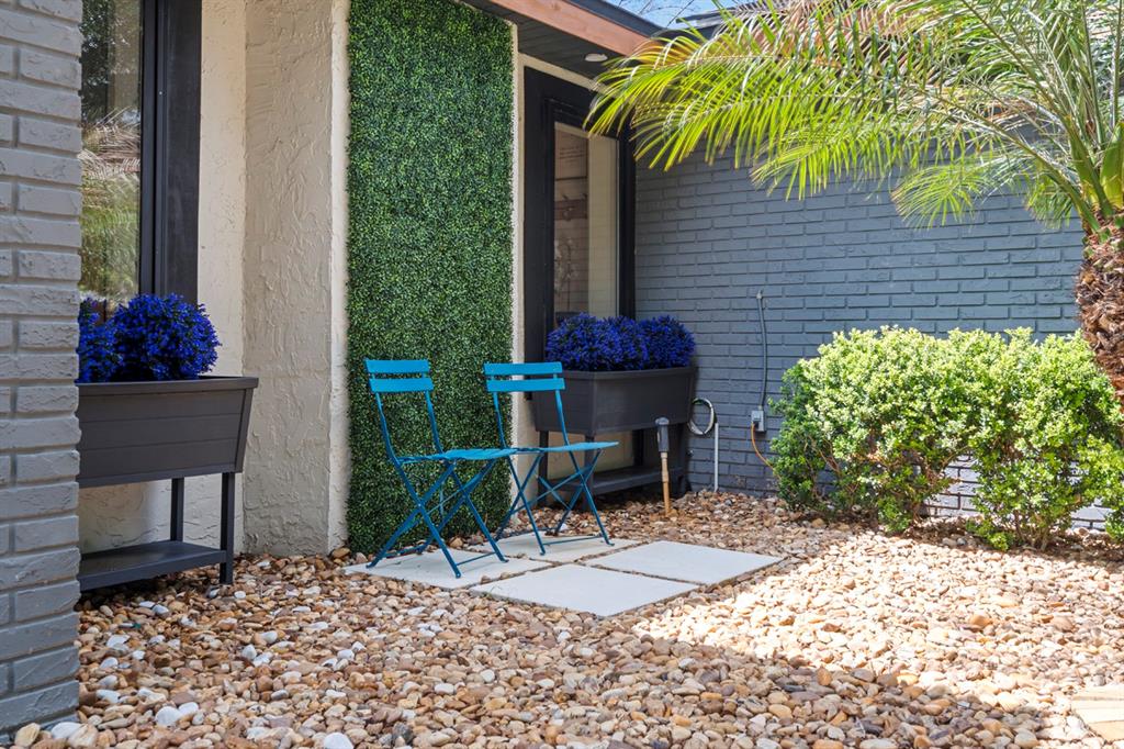A patio area features two blue chairs, potted blue flowers, and a green wall panel — 755 WOODSIDE ROAD, MAITLAND, FL