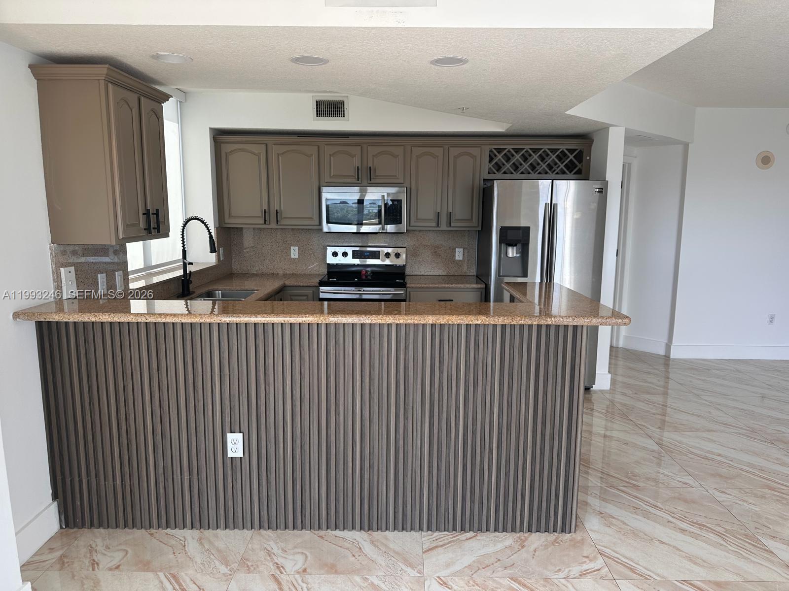 A kitchen features brown cabinets, granite countertops, stainless steel appliances, and a slatted breakfast bar — 4242 NW 2nd St # 1116, Miami FL 33126, MIAMI, FL