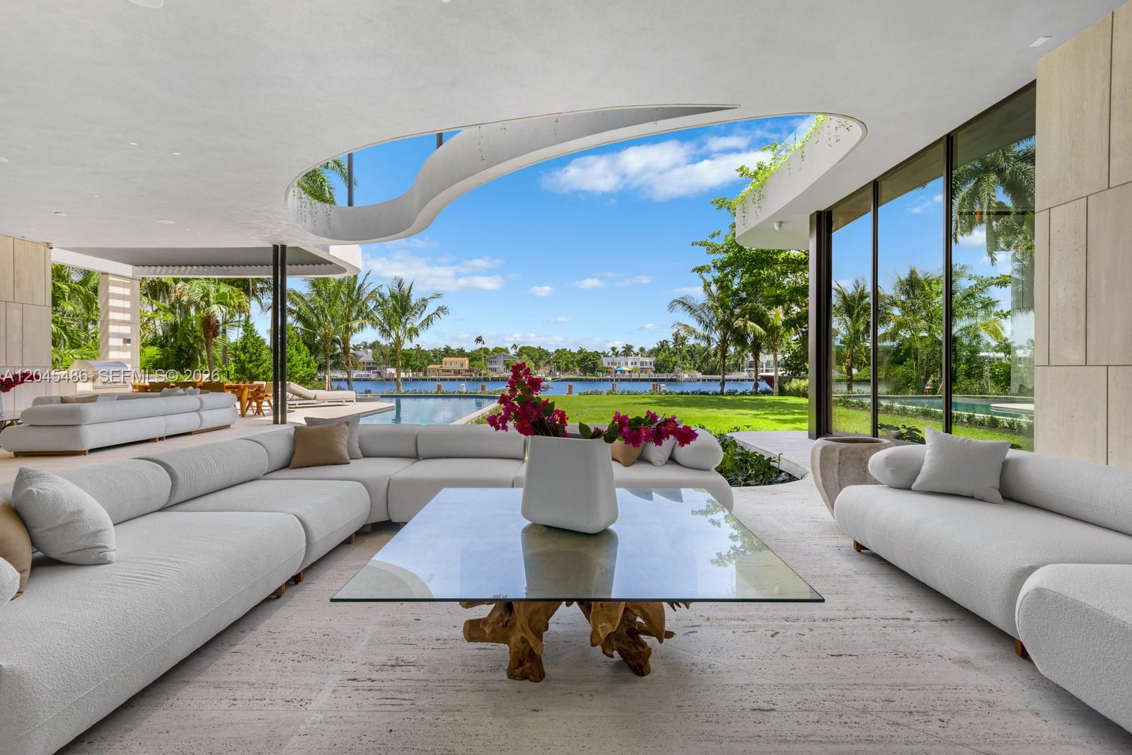 A modern open-air living room features a large sectional sofa, glass coffee table, and pool — 1015 S Southlake Dr, Hollywood FL 33019, HOLLYWOOD, FL
