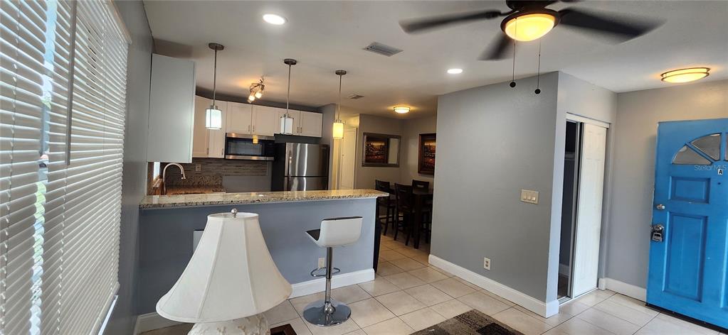 A kitchen with granite countertops and a breakfast bar opens into a dining area — 10706 N 15TH STREETS UNIT A, TAMPA, FL