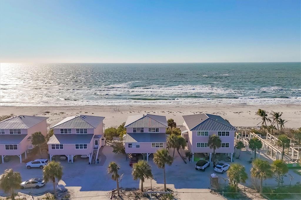 Three pink beach houses stand on stilts along a sandy shore overlooking the ocean — 290 GULF BOULEVARD UNIT 17, BOCA GRANDE, FL