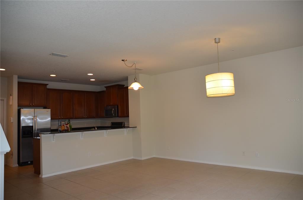 An open-concept kitchen with dark wood cabinets and a breakfast bar overlooks a dining area — 213 SILVERGLEN LANE, ALTAMONTE SPRINGS, FL