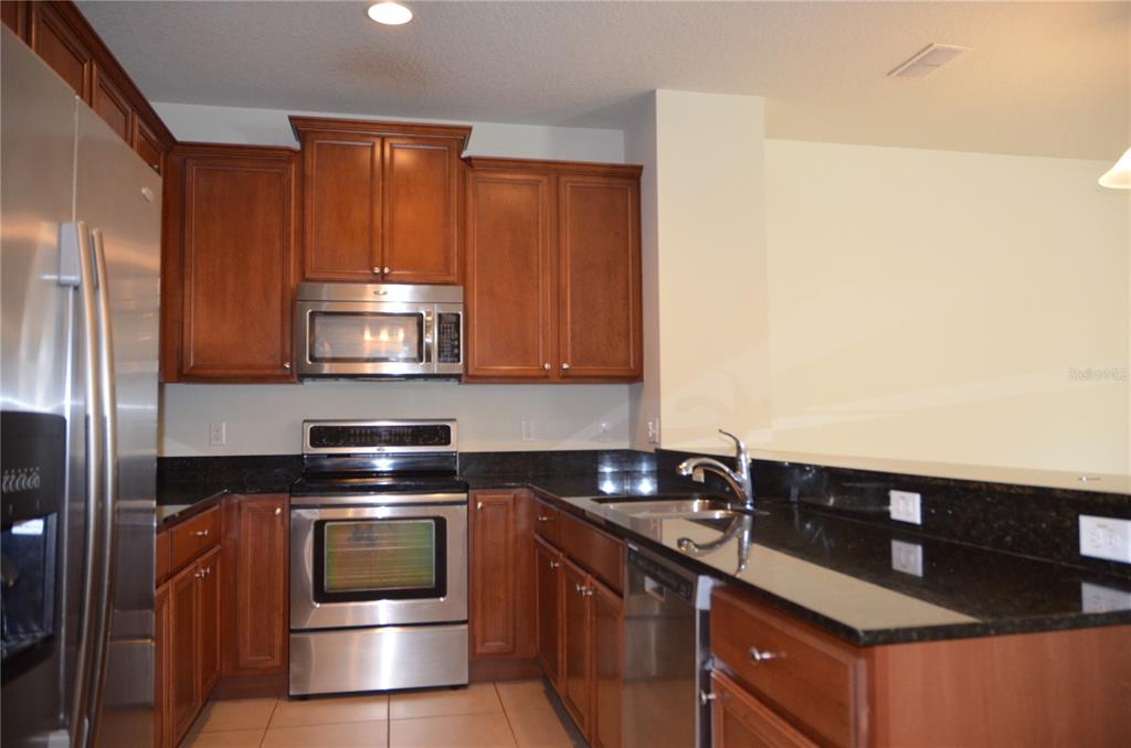 A kitchen features wood cabinets, stainless steel appliances, and black granite countertops — 213 SILVERGLEN LANE, ALTAMONTE SPRINGS, FL