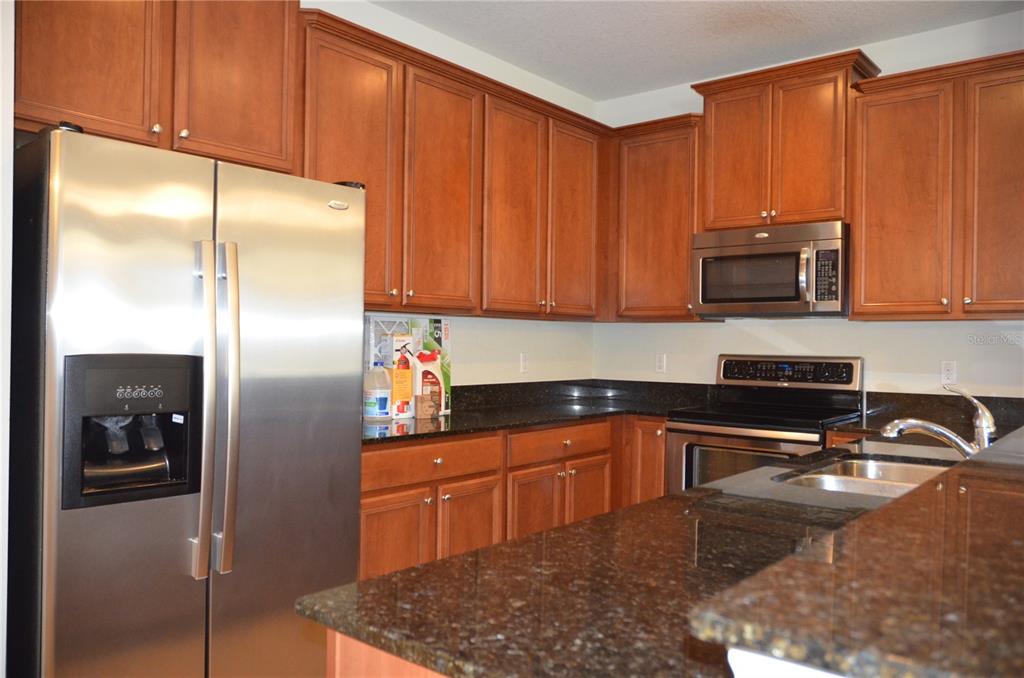A kitchen features wood cabinets, dark granite countertops, and stainless steel appliances — 213 SILVERGLEN LANE, ALTAMONTE SPRINGS, FL
