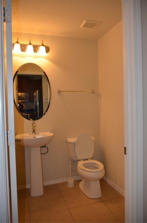 A small half bathroom features a pedestal sink, an oval mirror, and a white toilet — 213 SILVERGLEN LANE, ALTAMONTE SPRINGS, FL
