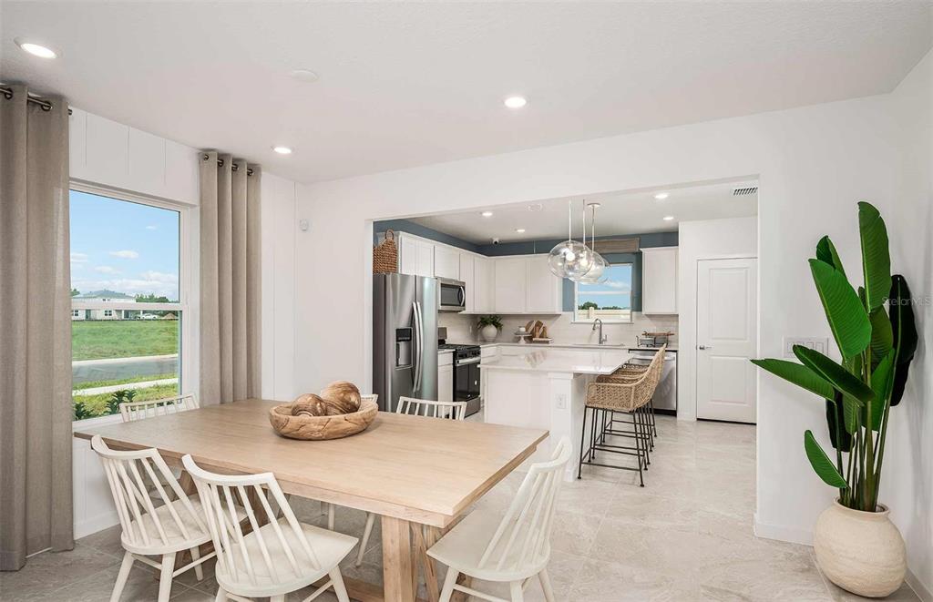A dining area with a wooden table opens into a kitchen with white cabinetry — 9147 NEWMONS PLACE, WILDWOOD, FL