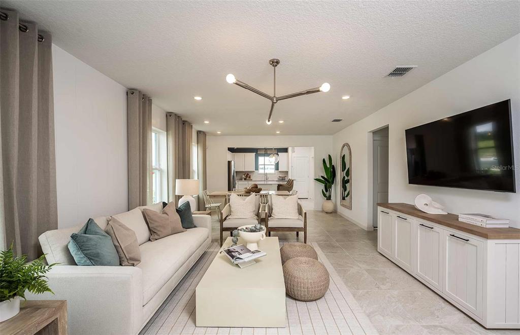 A living room features a white sofa, a modern chandelier, and a wall-mounted television — 9147 NEWMONS PLACE, WILDWOOD, FL