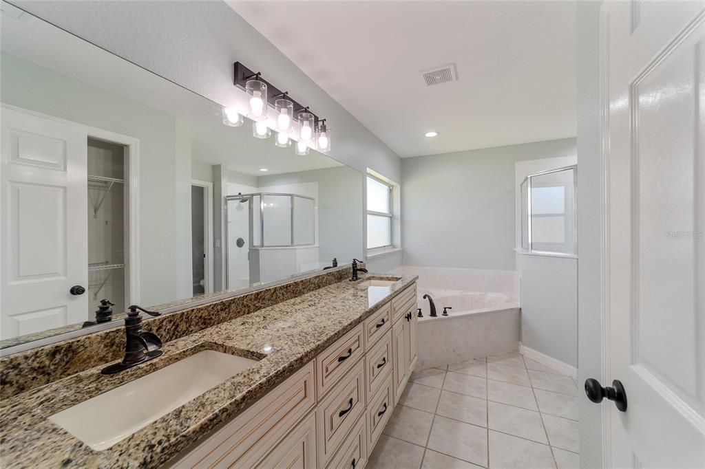 A bathroom features a double vanity with granite countertops, a soaking tub, and a shower — 4020 NE 14TH COURT, OCALA, FL