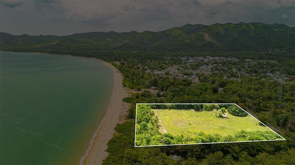 An aerial view shows a rectangular plot of land situated near a coastal beach — COMM. PLAYA, CARR. 401 KM. HM 1.9, ANASCO, PR